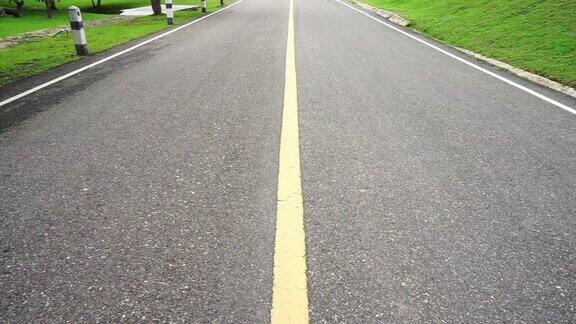 沥青路面透视与黄色线平移引导道路环绕着绿色的自然