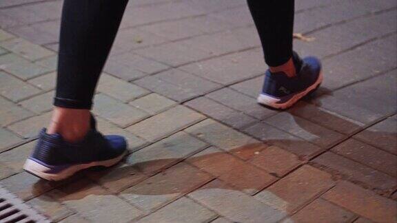 这个女孩晚上在城市的人行道上特写的腿