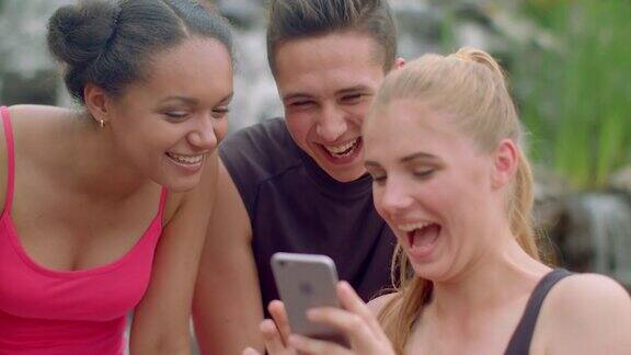 快乐的人们在户外使用手机开心的朋友在看手机上的照片
