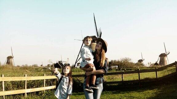 风车农场附近的一个欧洲家庭的肖像戴着帽子的漂亮女人带着小男孩和小女孩一起走4k