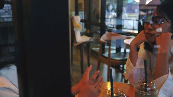 两个年轻的亚洲女人喜欢在咖啡馆聊天和使用智能手机的场景人们的生活方式亚洲女人的生活方式