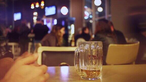 在酒吧里用智能手机喝啤酒的男人