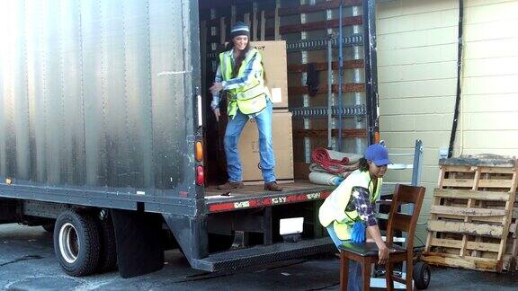 两名女工人正在把家具装上货车