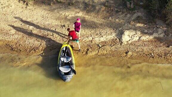 一对年轻夫妇在沼泽地的河岸上移动一艘充气独木舟4k西班牙纳瓦拉的阿罗兹水库