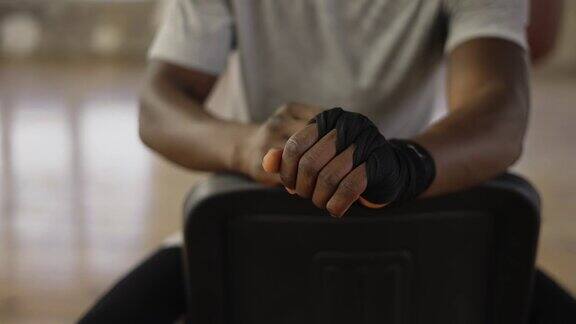 一个面目全非的美国黑人拳击手正在用黑色绷带包扎双手