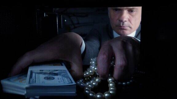 一名男子从保险箱里拿出美元和珠宝