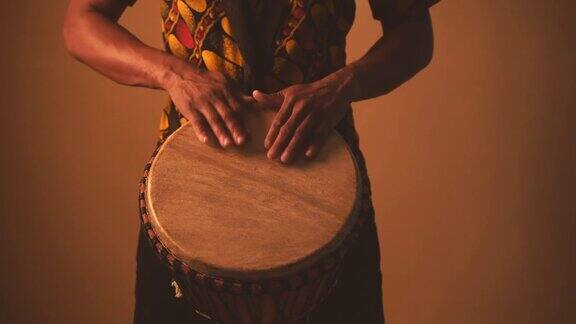 非裔美国男子音乐家在棕色背景下弹奏传统鼓的细节