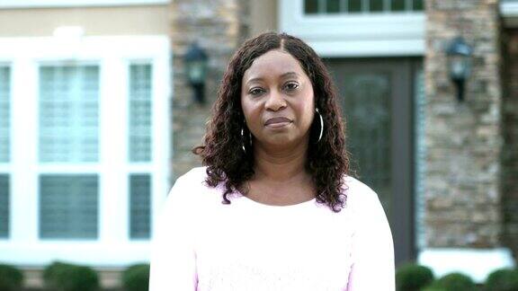 成熟的非裔美国女人站在屋前