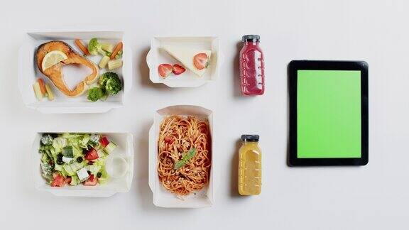 食品配送应用程序俯视图在白色背景上一次性容器带走的饭菜特写的午餐盒与煮熟的沙拉意大利面和蛋糕部分小工具与色度绿色屏幕