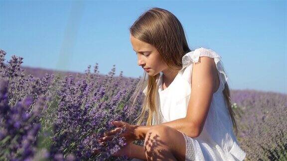 可爱的小女孩在薰衣草花的田野里穿着白色的裙子