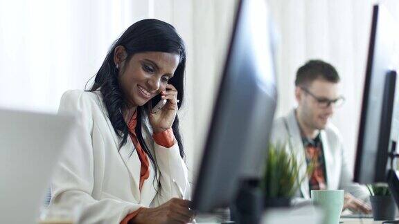 微笑的女商人在办公室里讲电话