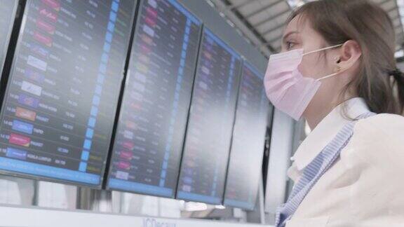 20-30岁的亚洲裔女性在新冠肺炎疫情下使用智能手机在机场旅行新冠肺炎封锁和旅行重新开放后的新常态办公生活方式