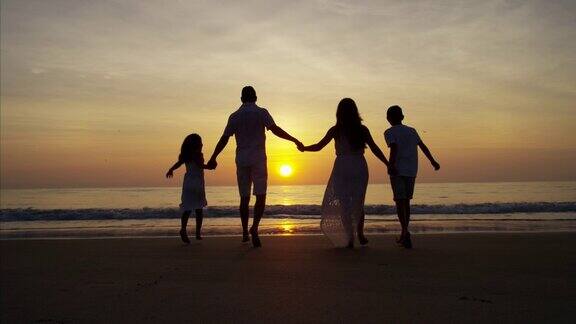 日出时海边西班牙一家人的剪影