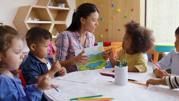 欢快的老师在美术课上指导她多样化的幼儿园班级