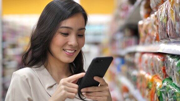 亚洲女人在超市使用智能手机