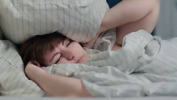 女人因为噪音睡不着觉晚上用枕头捂住耳朵
