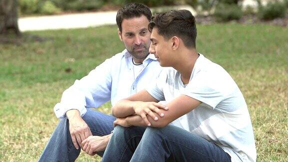 父亲和儿子坐在草坪上聊天