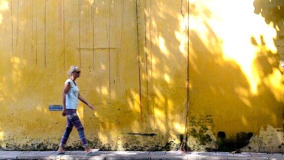 年轻女子走在黄墙前