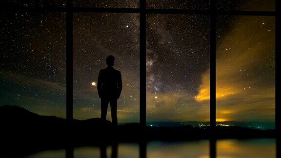 在星空背景下站在窗前的商人时间流逝