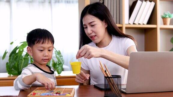 多任务亚洲母亲一边在家工作一边照顾孩子生活方式单身母亲快乐地养育儿子花时间教孩子画画一起爱和温柔现代女性的生活方式理念