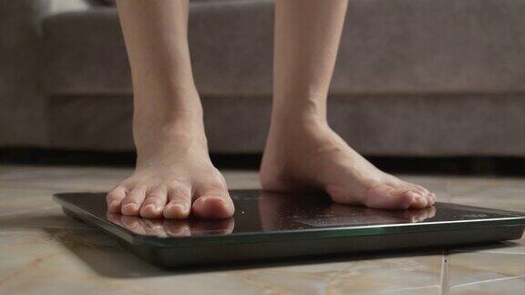 亚洲女性脚踩在数字体重秤上检查她的体重