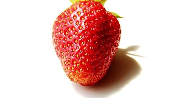 一颗新鲜的红草莓在白色的背景下旋转