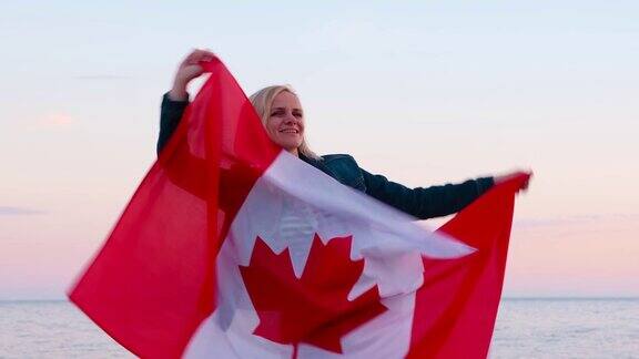 4k微笑的女人挥舞着加拿大国旗在户外海洋海洋日落在夏天-加拿大国旗国家爱国主义7月1日