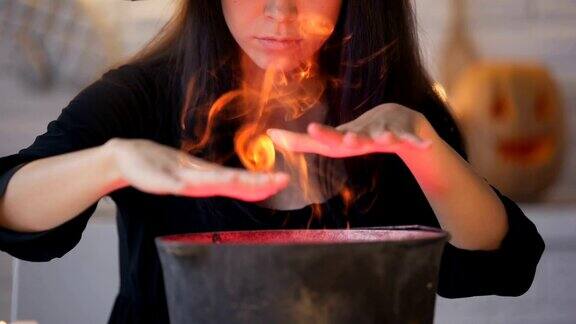 年轻的女巫在黑衣变戏法和烹饪药水万圣节前夕的魔法