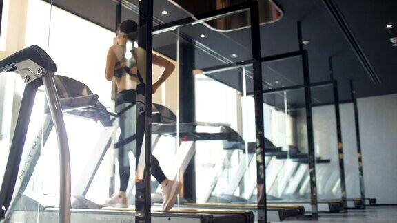 在跑步机上跑步的女人新常态和现代健身房