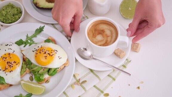 一杯热咖啡和新鲜做的健康吐司配牛油果和煎蛋