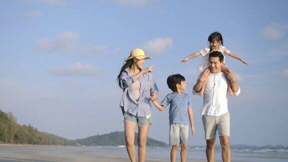 快乐的亚洲家庭享受和走在海滩上的暑假缓慢的运动家庭假期和旅游