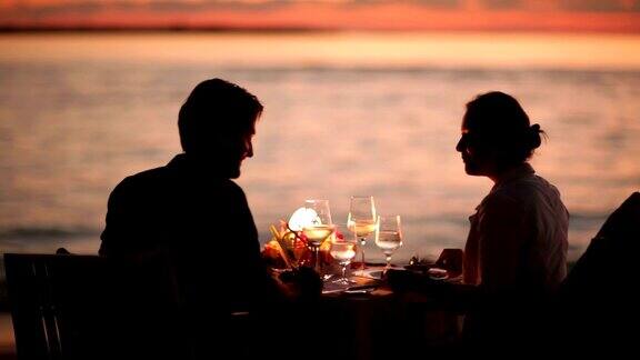一对情侣在日落时分的海滩上用餐