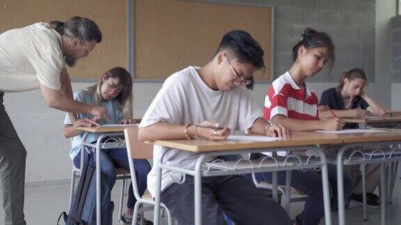 亚洲青少年学生参加考试在大学高中考试期间老师给学生讲解习题
