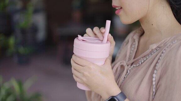 一个陌生的亚洲女人用硅胶旅行杯喝水
