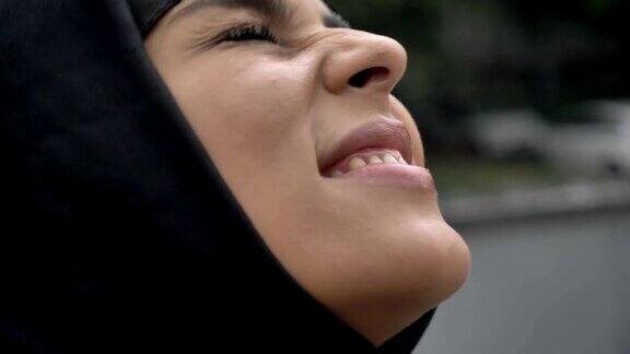 年轻的穆斯林妇女戴着头巾站在雨中宗教观念天气观念侧视