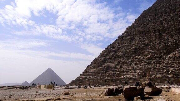 埃及吉萨金字塔的美丽景色我们可以看到云朵在联合国教科文组织分类的纪念碑上方埃及人在金字塔前行走