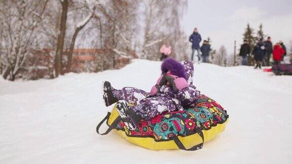 快乐的妈妈和女儿在冬天的雪地里玩雪橇和打雪仗母亲和孩子笑和高兴滑翔在一个充气管圣诞节期间全家游玩公园慢动作