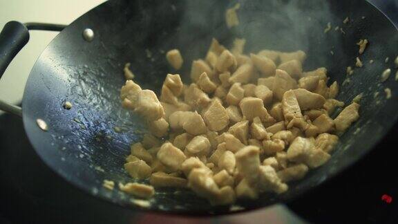 在厨房炉子下面的热锅里搅拌鸡块准备食物烹饪蛋白质