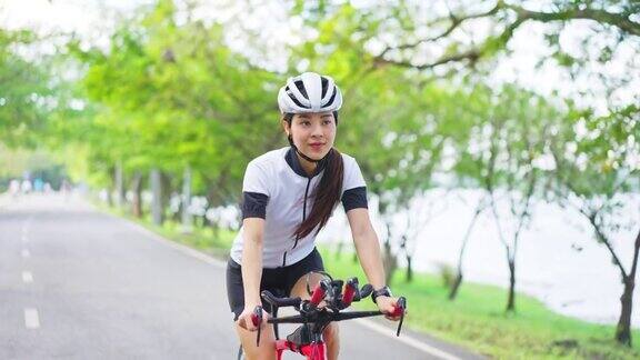 亚洲年轻美丽的女人骑自行车为健康在晚上在公共公园运动员健康和坚定的女孩在运动服装锻炼通过自行车锻炼运动为她的健康健康