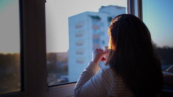 女人在阳台上喝着咖啡看日落欣赏日落