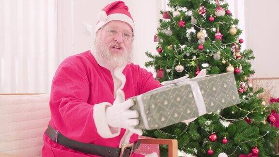 年迈的圣诞老人穿着圣诞服装手持圣诞礼盒
