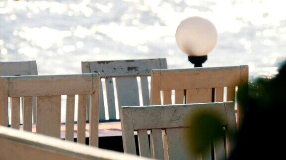 空荡荡的咖啡馆白色的木椅放在海边海浪向阳光倾泻而下海边的咖啡桌