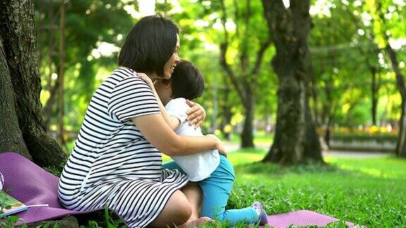 孕妇带着孩子在户外母亲和儿子在夏季公园的自然背景小男孩拥抱着第二次怀孕的母亲怀孕、新生活、家庭、亲子观念