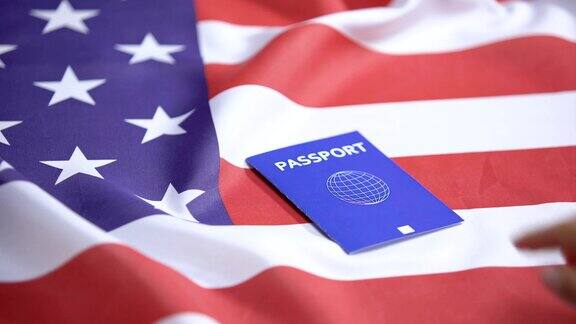 女性手将国际蓝色护照放在美国国旗上签证申请人