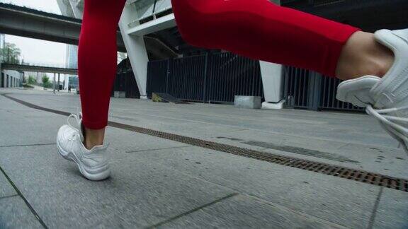 近距离观察女性跑步者在城市街道上慢跑的双腿运动女孩训练跑步