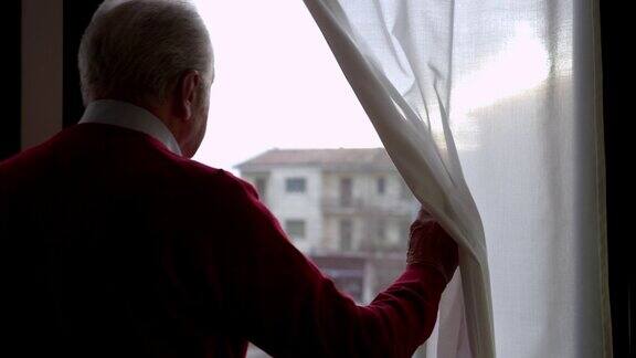 一位忧心忡忡的老人拉开窗帘向窗外望去