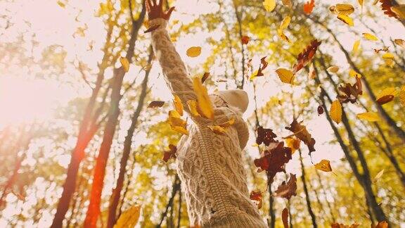 MS超级慢镜头无忧无虑的年轻女子纺纱在飘落的金秋树叶在森林