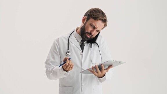 不高兴的男子医生与听诊器工作的病史和通话的智能手机