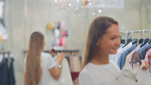 一个快乐的女人正对着商店的一面大镜子试穿东西她笑了时尚和现代的服装精品