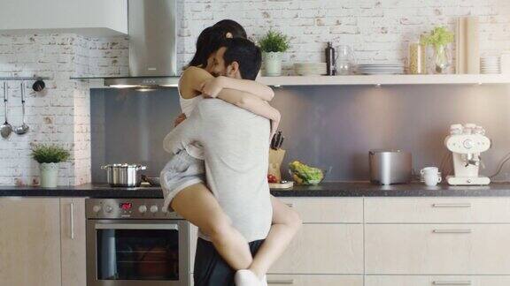 厨房里的幸福夫妻女孩跳进男孩的怀抱